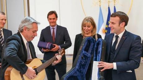 Alberto Fernández probando la guitarra que le regaló Macrón